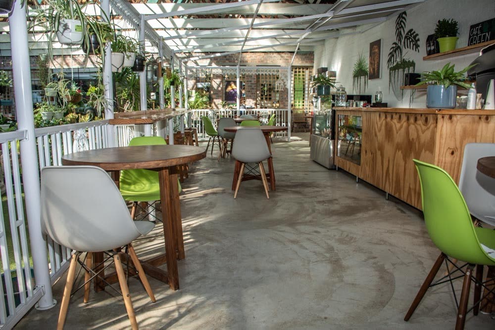 The coffee stop inside the nursery, white chairs and wooden tables among plants