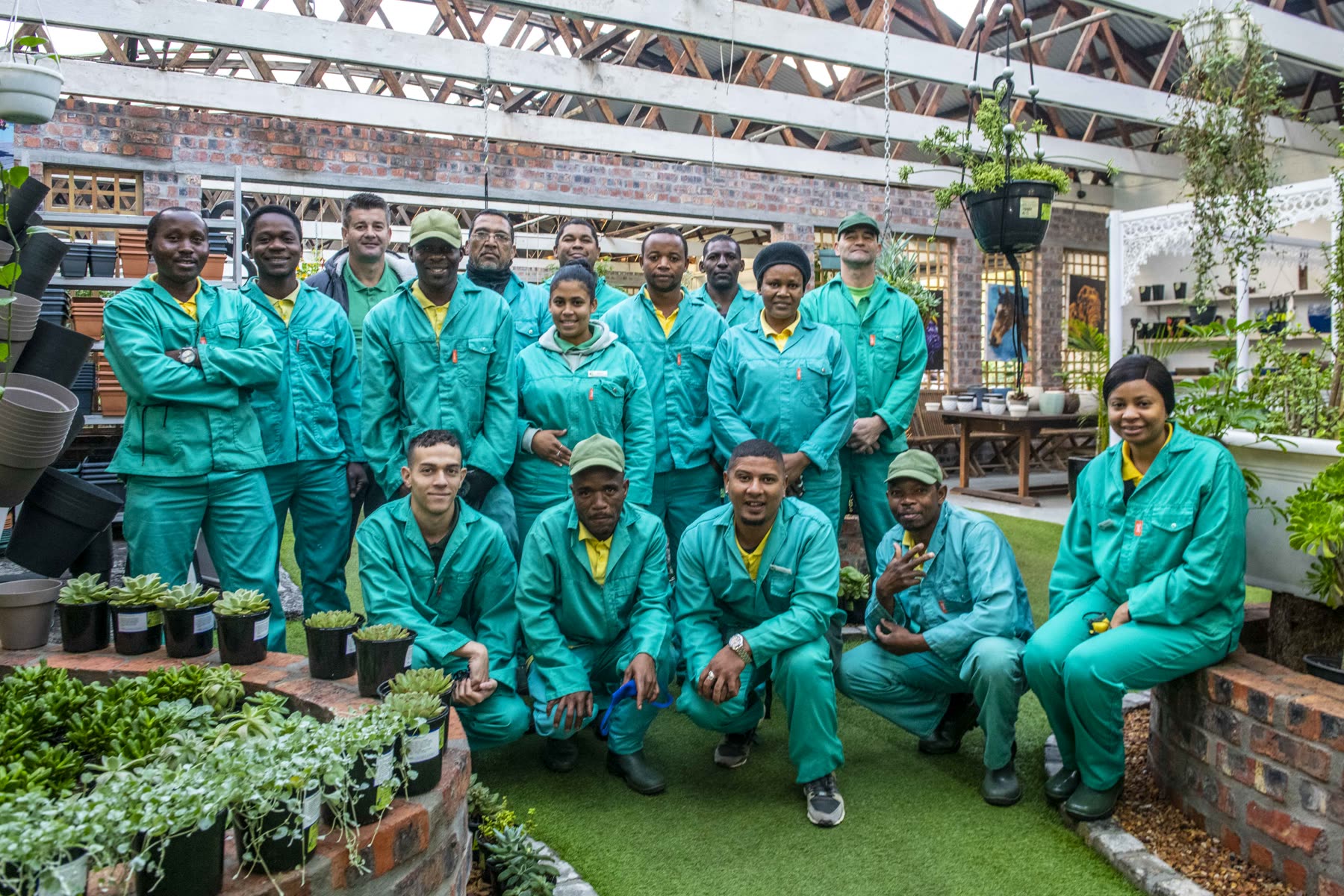 The Landscape Art team in teal work suits on the lawn inside the nursery